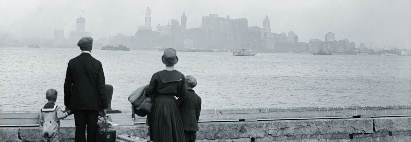 A family of immigrants looks across the bay at New York City.