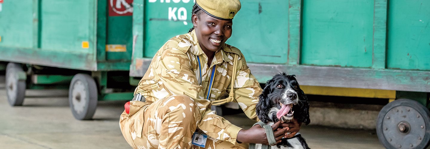 An officer smiles with her sniffing dog.