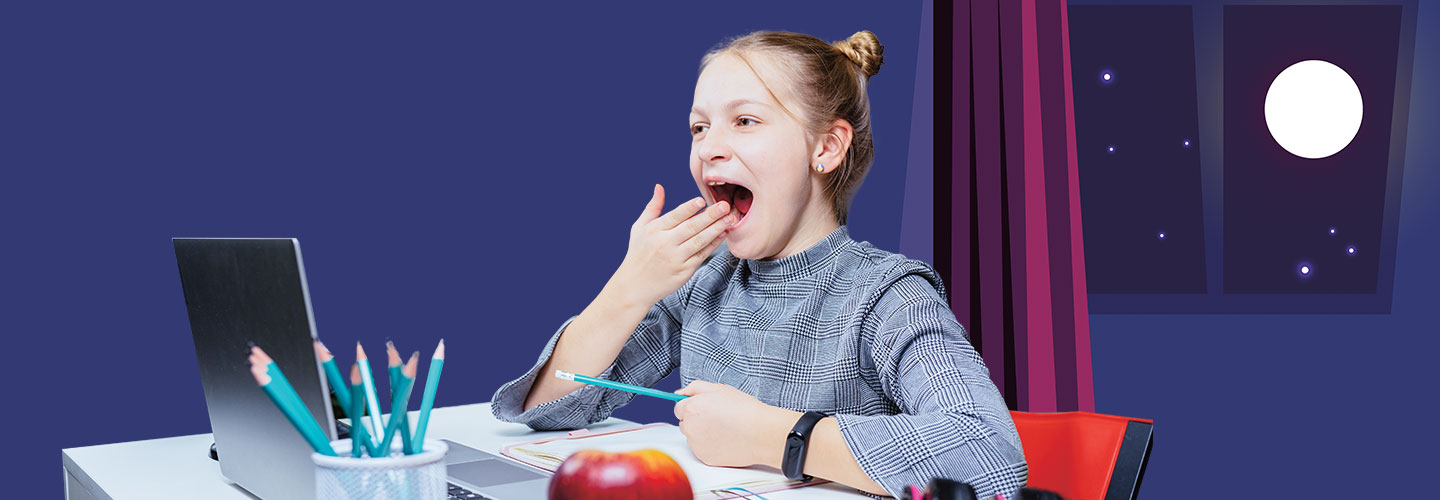 A young girl yawns while doing homework at night.