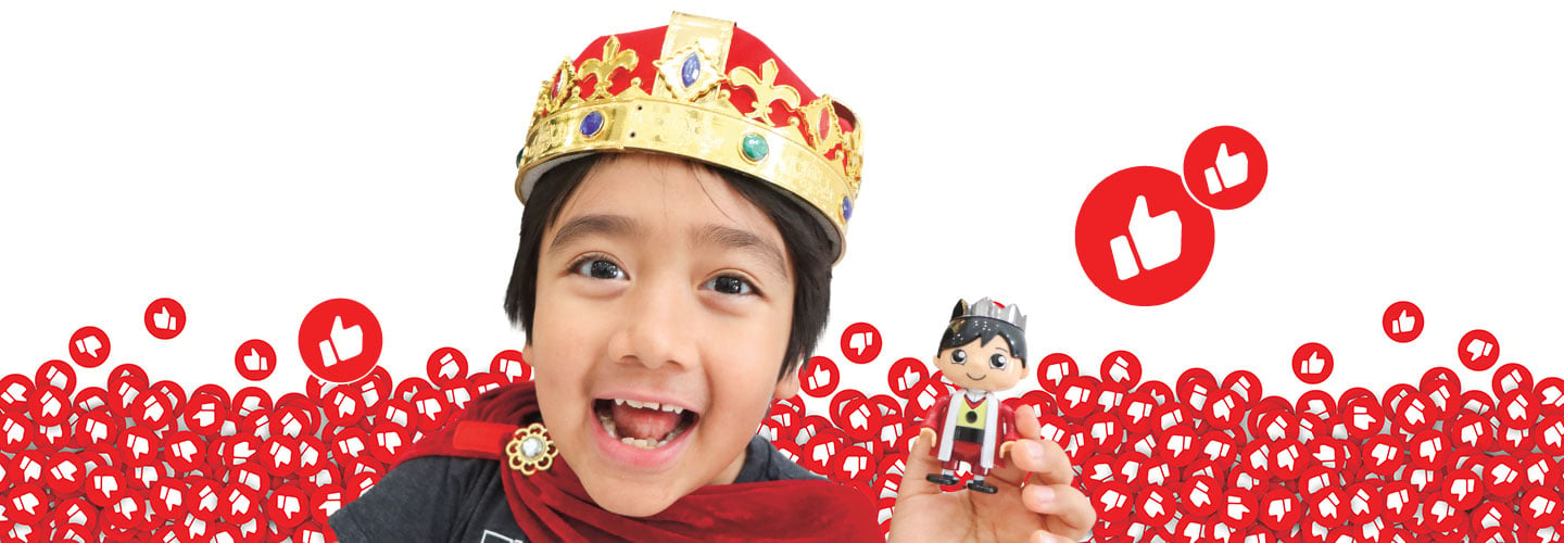 Ryan Kaji wears a crown and holds a toy that looks like him