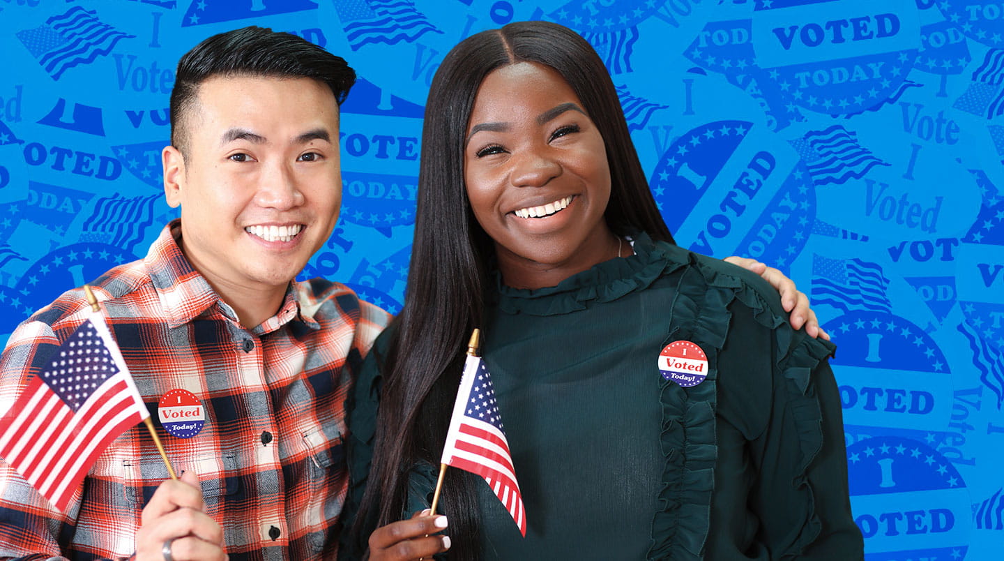 Two people smile while holding American flags and wearing I voted stickers