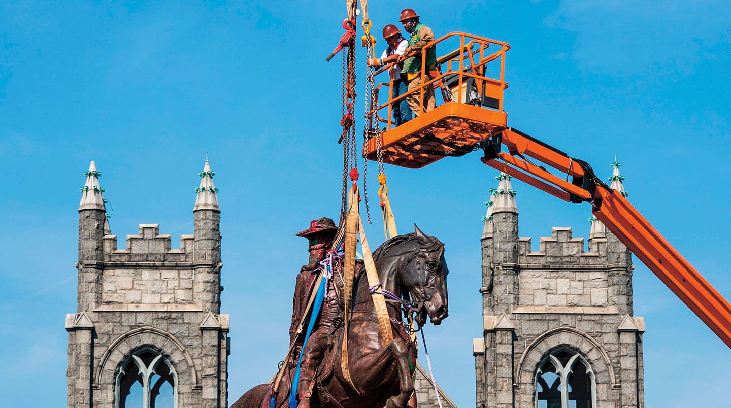 Workers lift away a statue of general Stuart riding a horse.