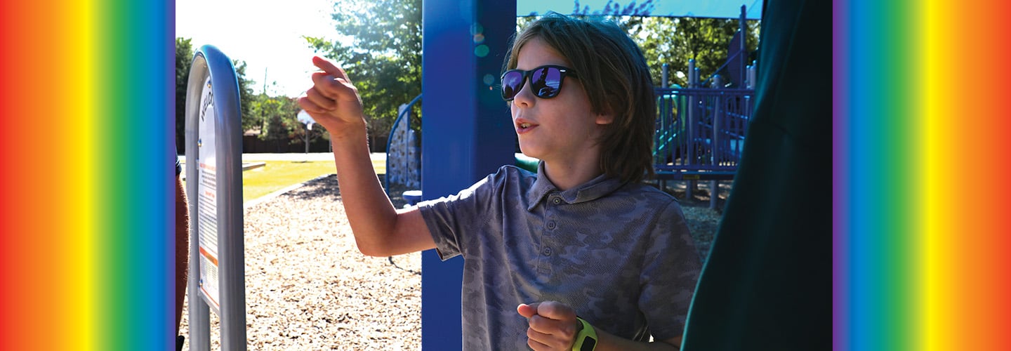 Photo of a kid with sunglasses playing at a playground