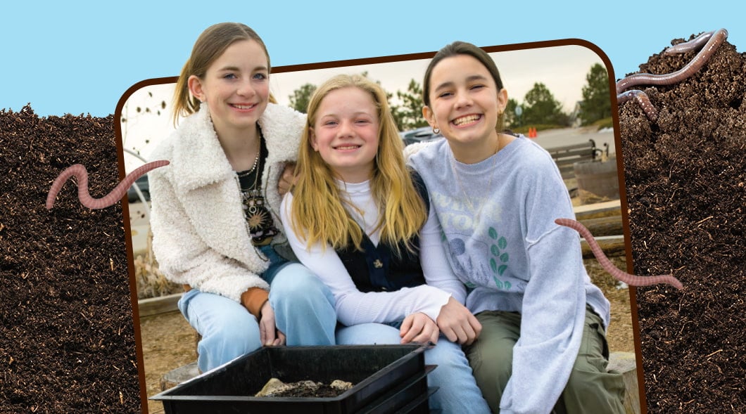 Image of three friends posing for photo against backdrop of dirt and worms