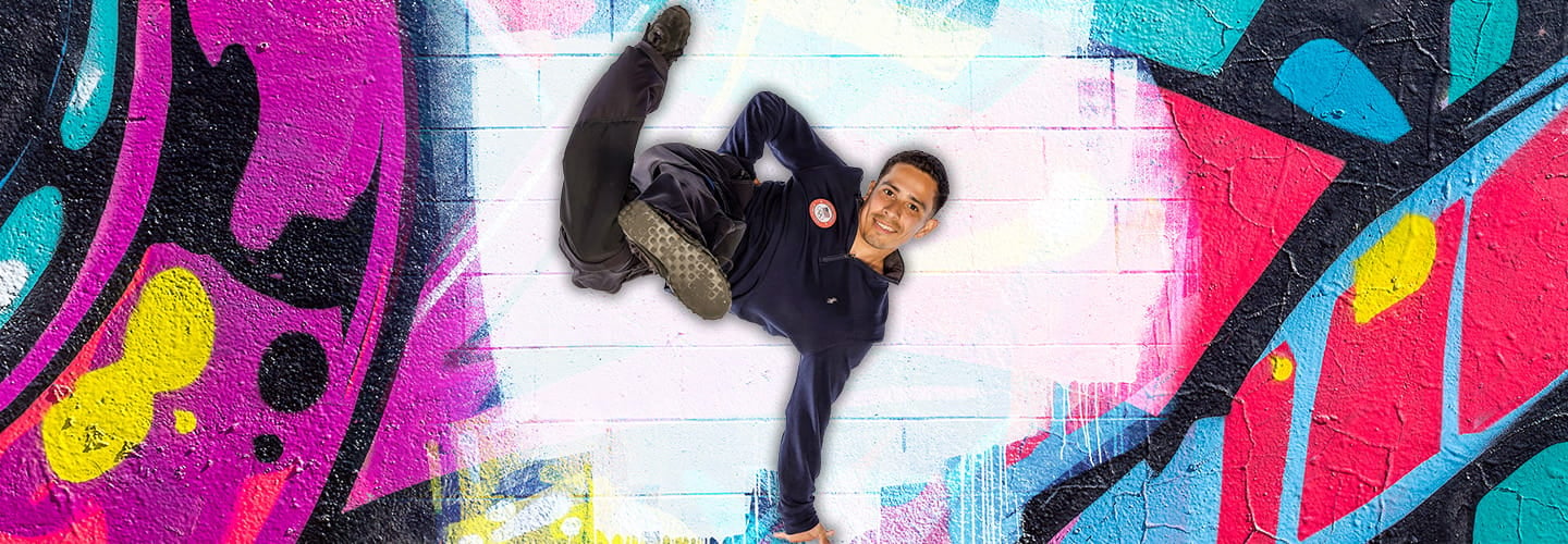 Image of a person break dancing in front of a graffiti wall