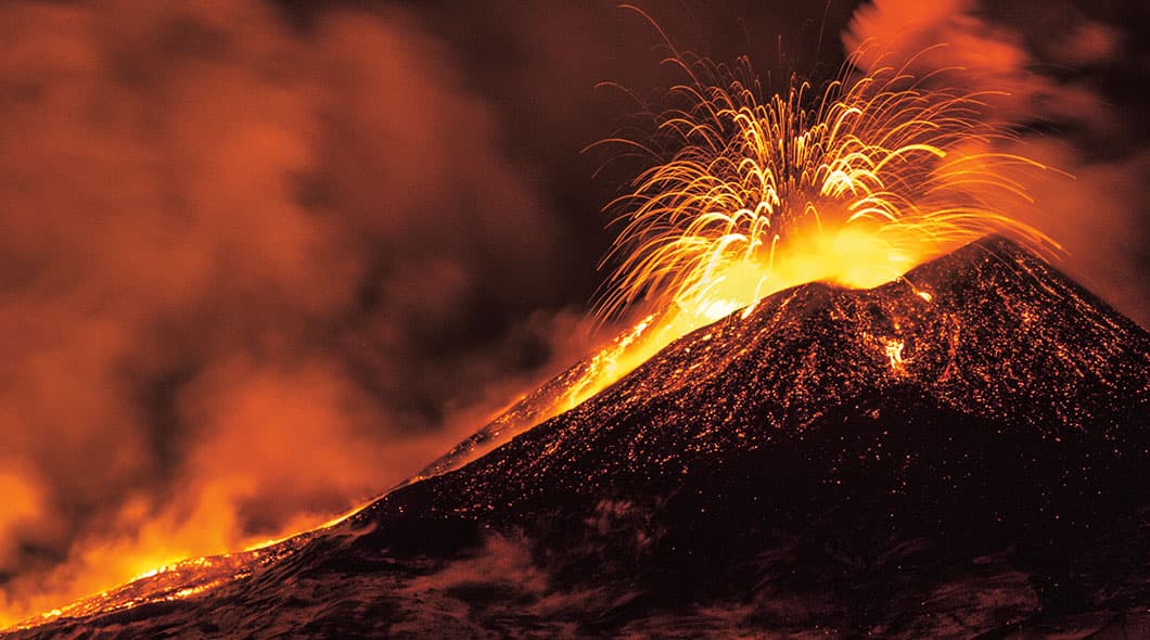 Volcano erupting with bright orange lava and sparks shooting from the crater