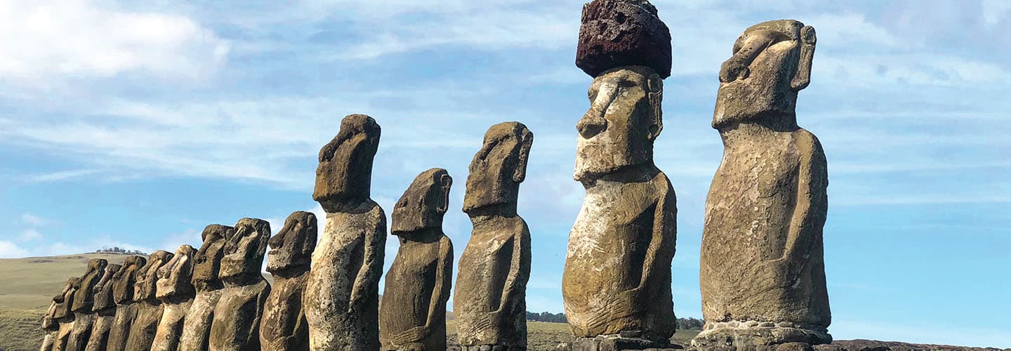 Row of moai statues on Easter Island against a blue sky