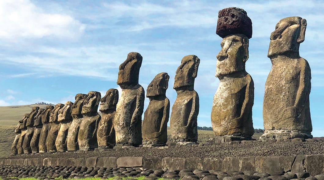 Row of moai statues on Easter Island against a blue sky