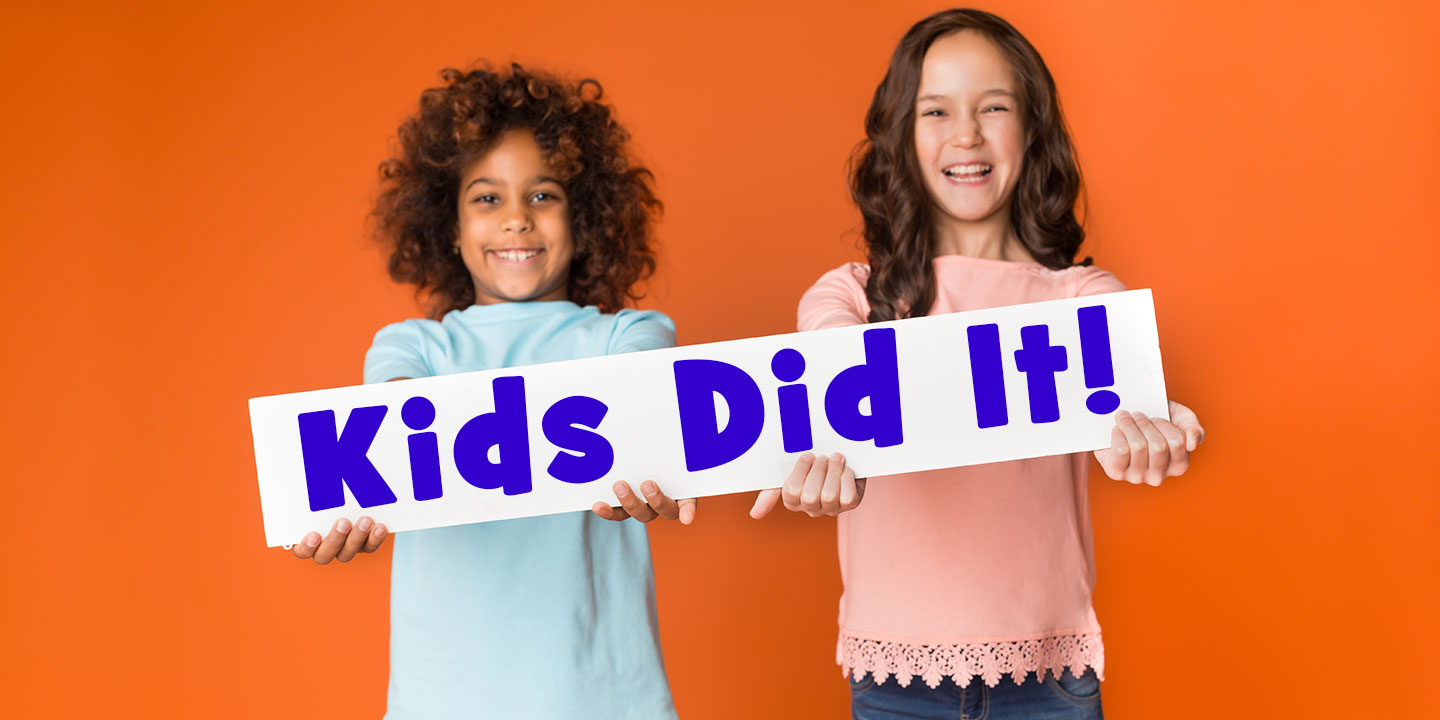 Two smiling young girls holding up sign that says "Kids Did It"